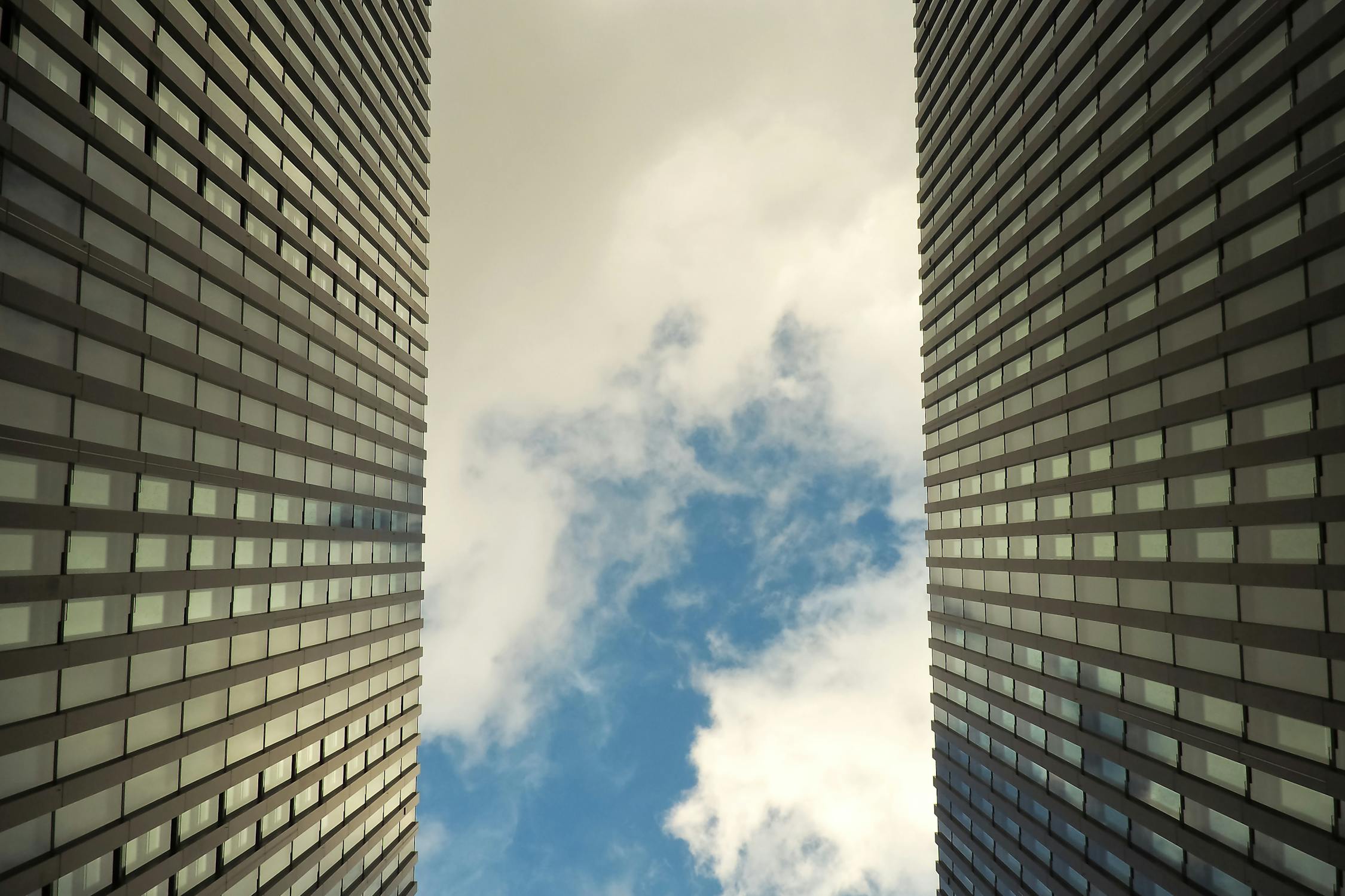 Façade de tour de verre en contre-plongée, symbolisant la structure et la transparence du statut JEI