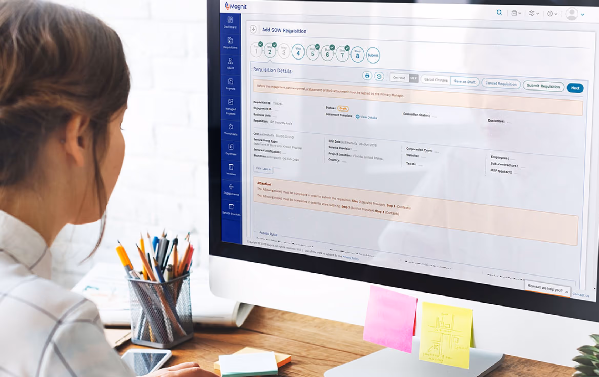Person working on a desktop computer displaying a requisition form interface with detailed fields and navigation steps.