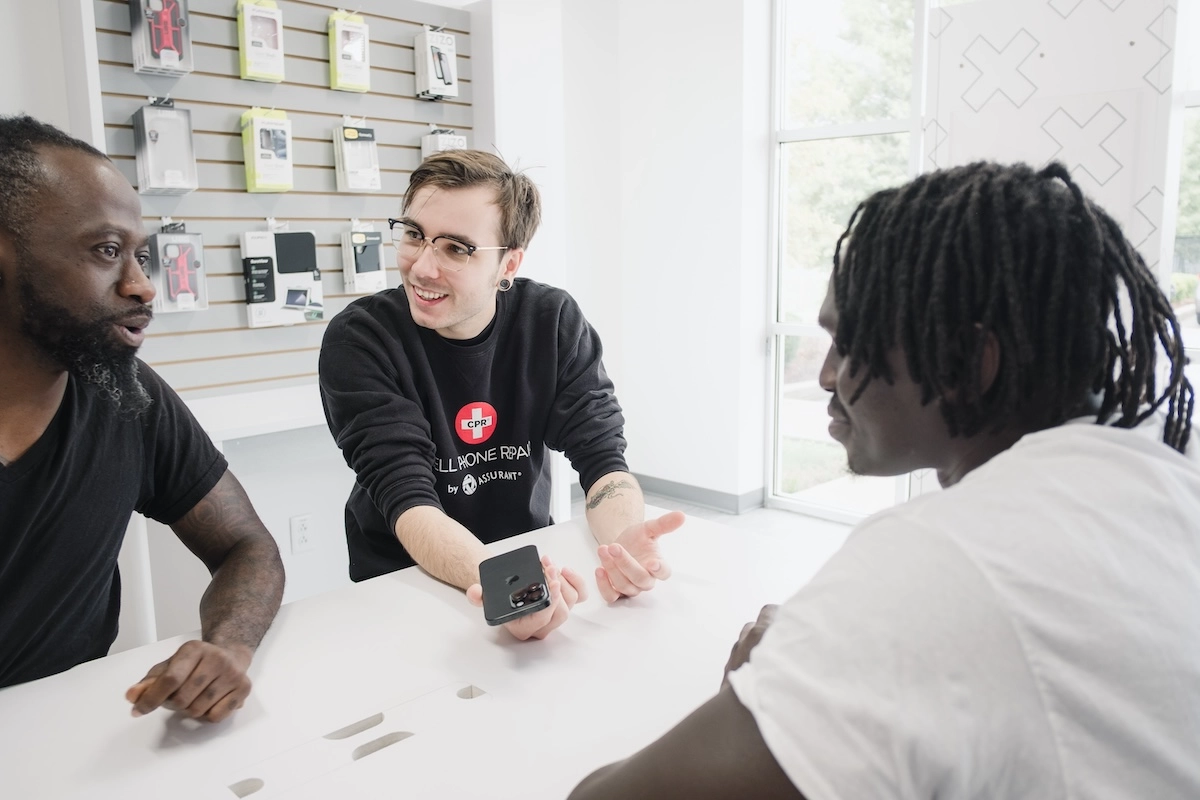 Cell Phone Repair technician assisting customers with a mobile device at a service counter