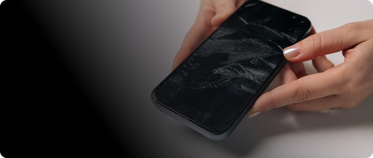 Hands holding a smartphone with a cracked screen for CPR common phone, computer, tablet and console repair issues