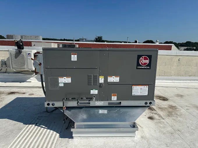 Rheem commercial rooftop HVAC unit mounted on a flat white roof under a clear blue sky.