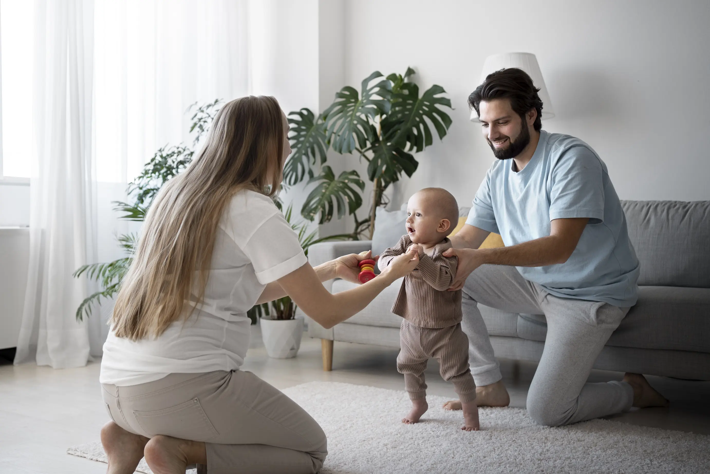 A baby maiking the first steps with parenst holding the hands.