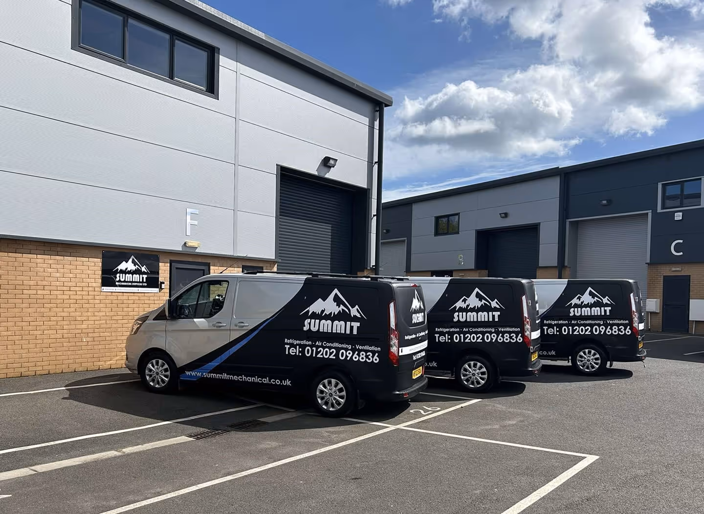 Three Summit Mechanical Services vans parked outside our head office in Poole under a partly cloudy sky.