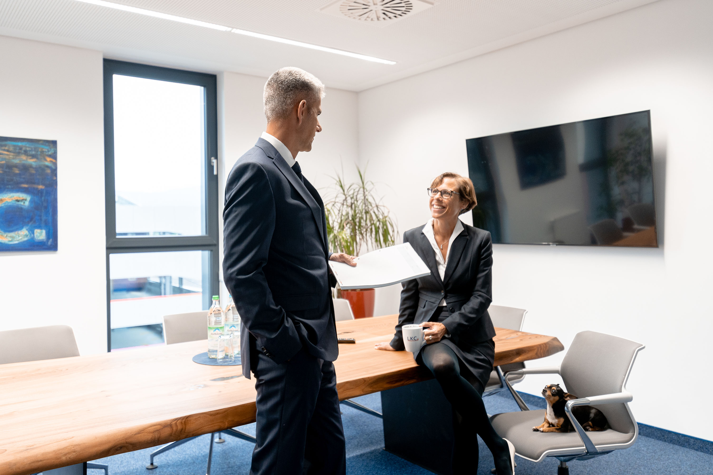 Zwei Personen im Büro stehen vor einem Bildschirm und besprechen etwas.