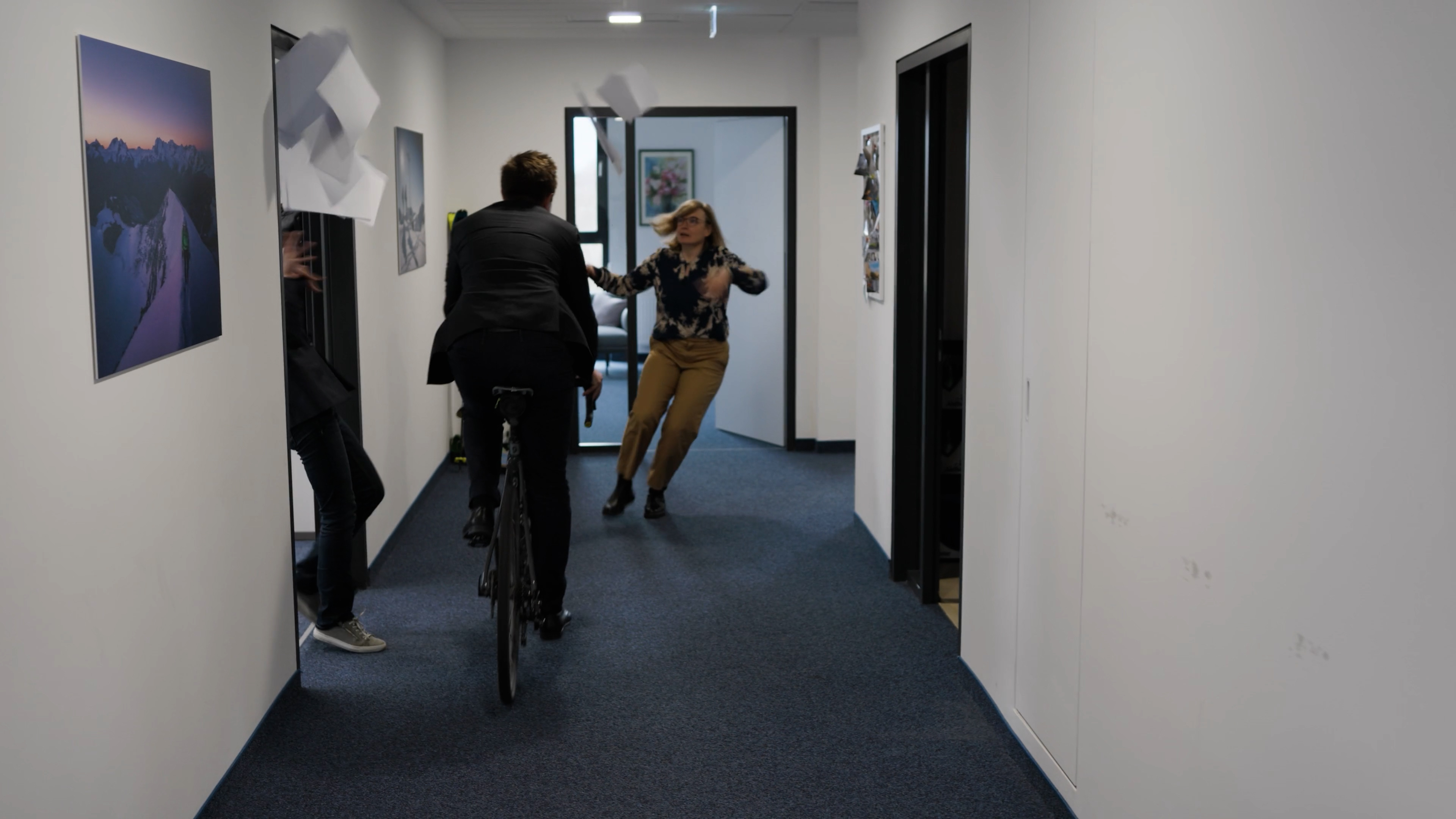 Zwei Personen mit Kamera-Equipment gehen einen Büroflur entlang.