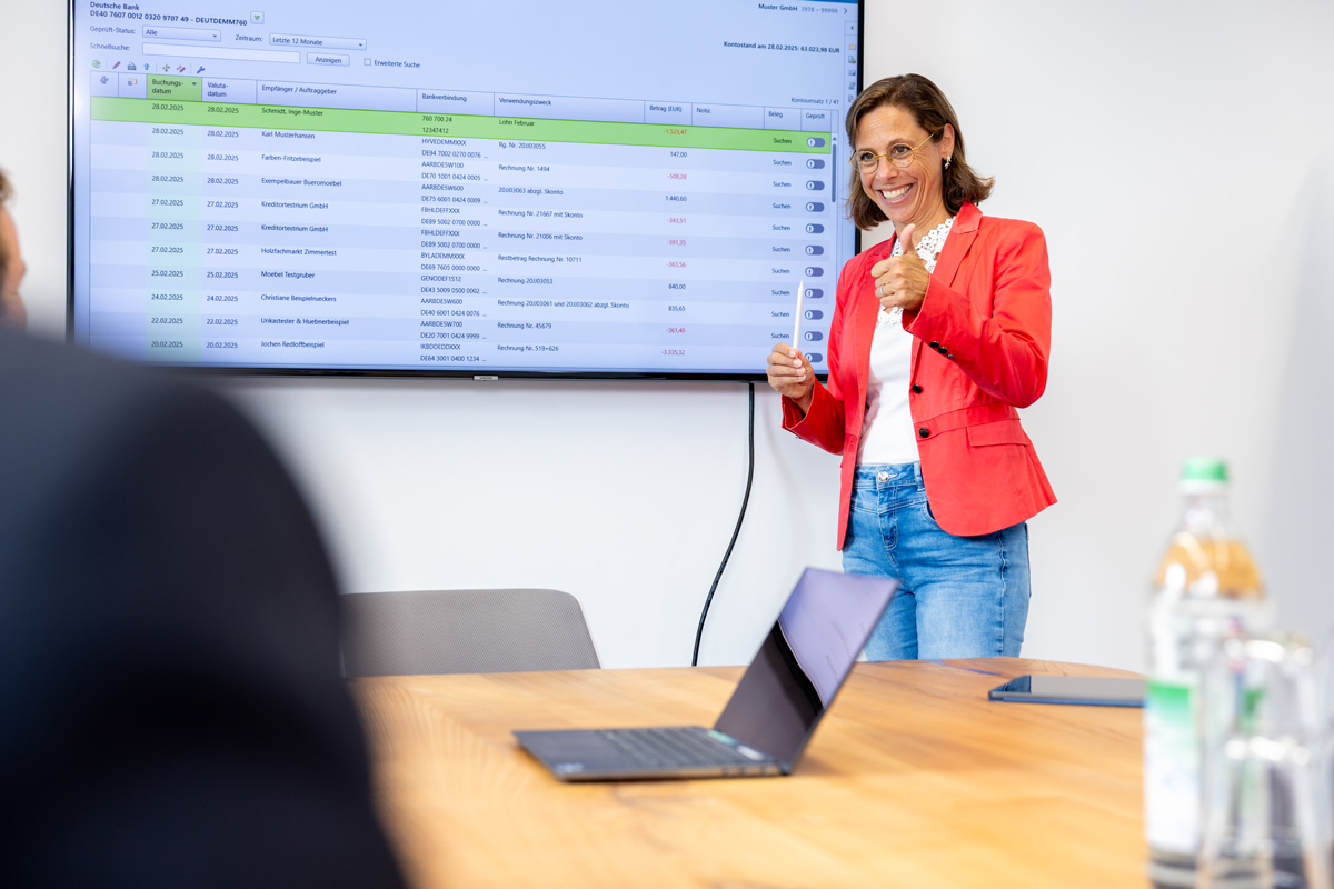 Frau präsentiert im Konferenzraum, im Hintergrund eine große Leinwand mit Diagrammen.