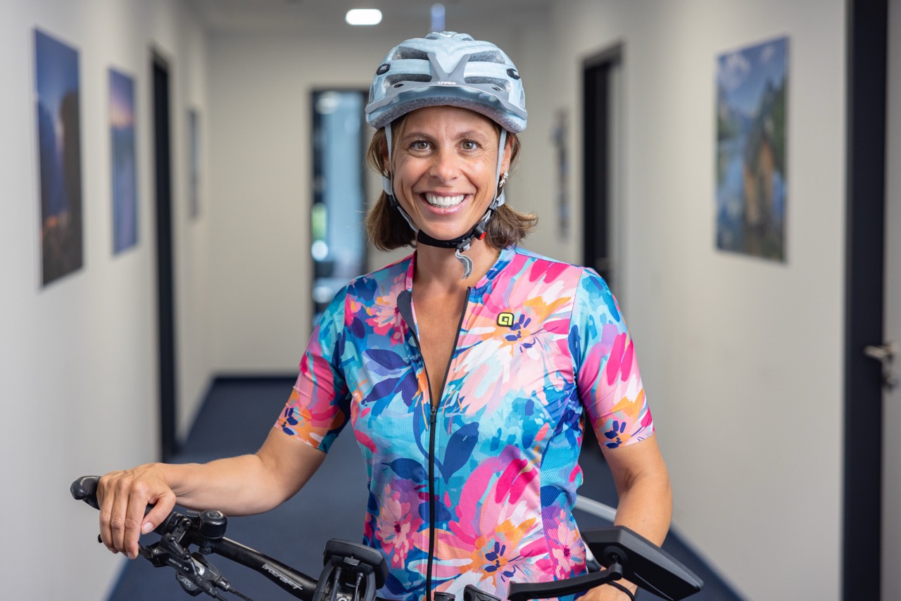 Frau im Flur mit Fahrradhelm hält einen Fahrradlenker.