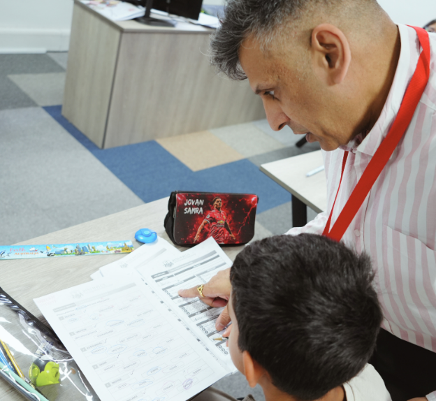 Teacher assisting a student with a worksheet in a classroom setting, showing personalised learning support and academic guidance