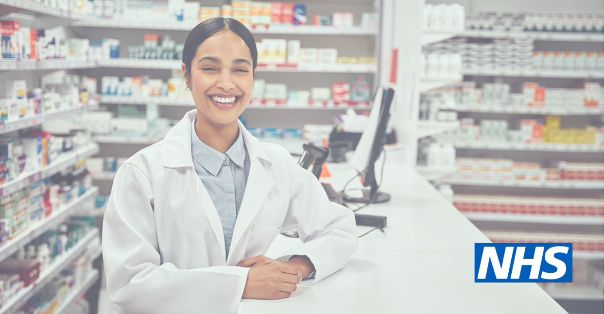 NHS pharmacist smiling behind the counter in a busy pharmacy setting supporting a health awareness digital campaign strategy.