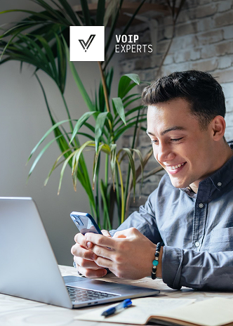 Professional using a smartphone beside a laptop, reflecting targeted VOIP marketing strategies.