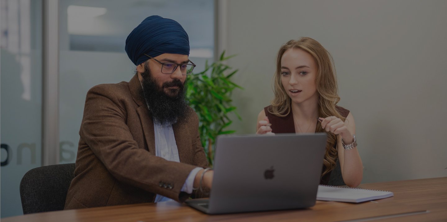 In a business meeting, a man and woman collaborate on website development, using a laptop for reference.