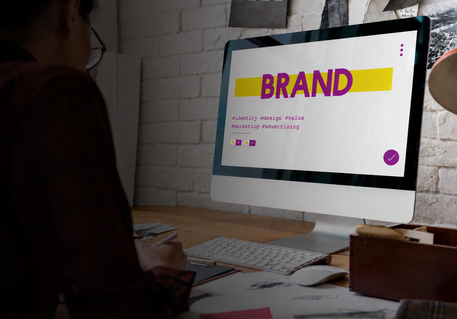 Designer sketching logo concepts on a branding layout sheet at a workspace.