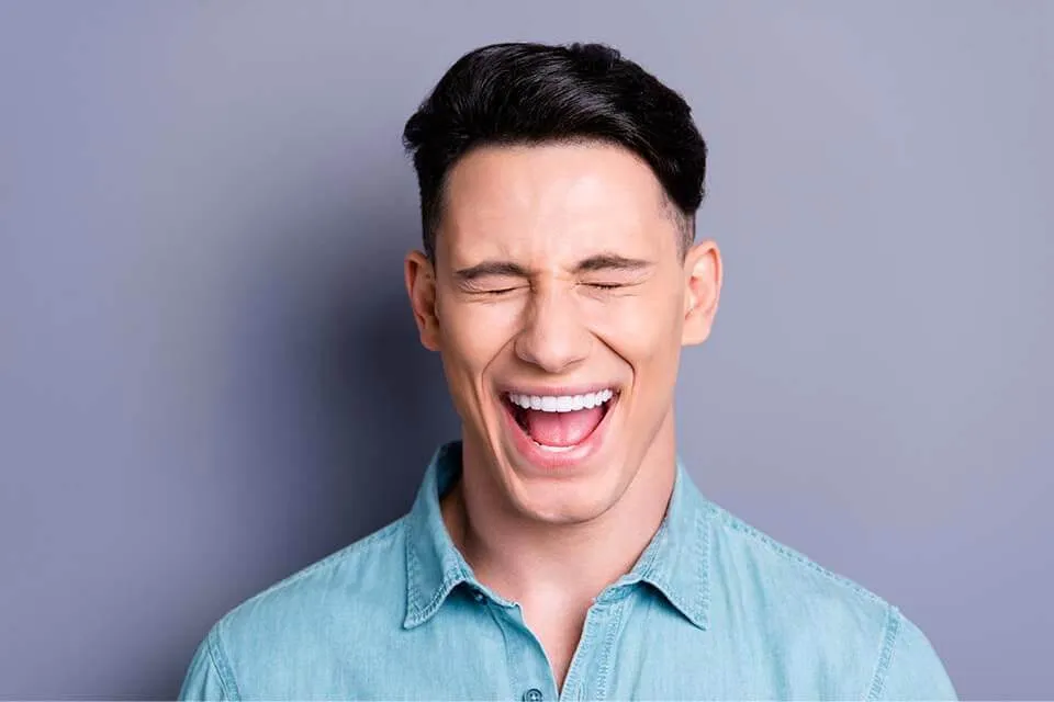 A man laughing with his eyes closed.
