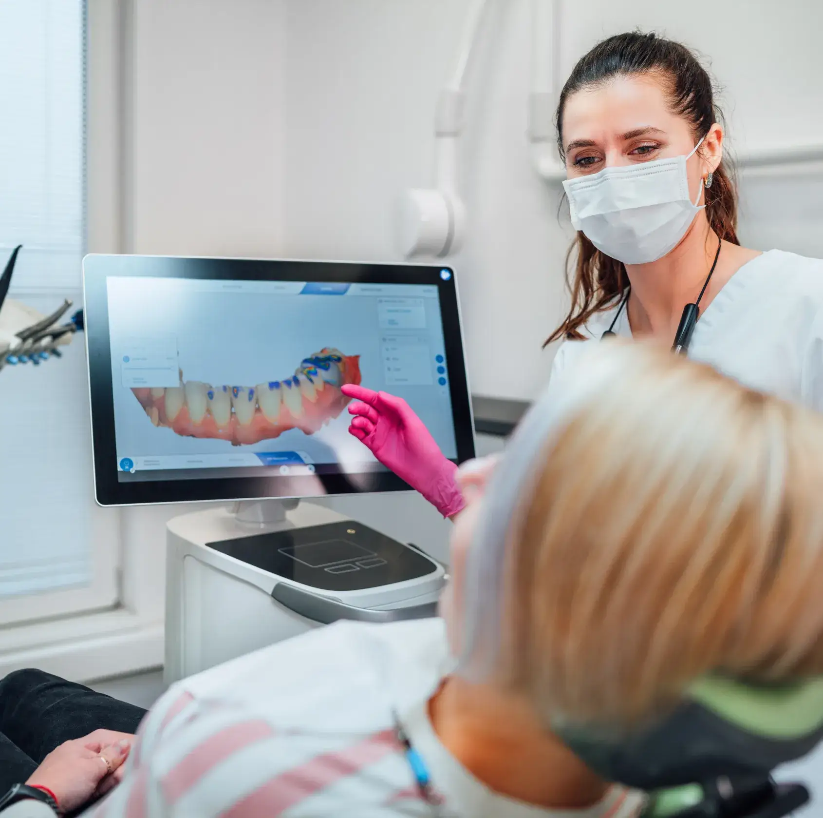 Dentist showing a digital dental scan to a patient on a screen during a consultation.