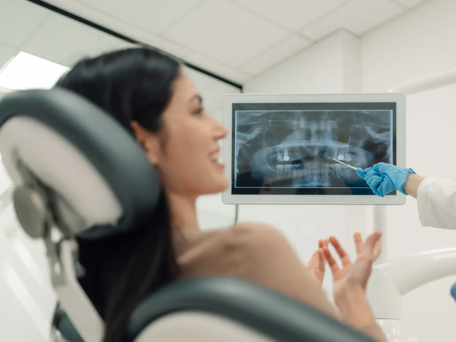 A dentist shows a female patient her dental X-ray on a screen during a check-up.
