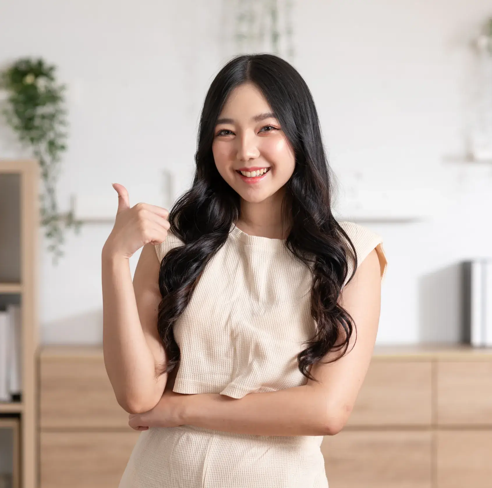 Woman smiling and giving a thumbs-up gesture indoors.