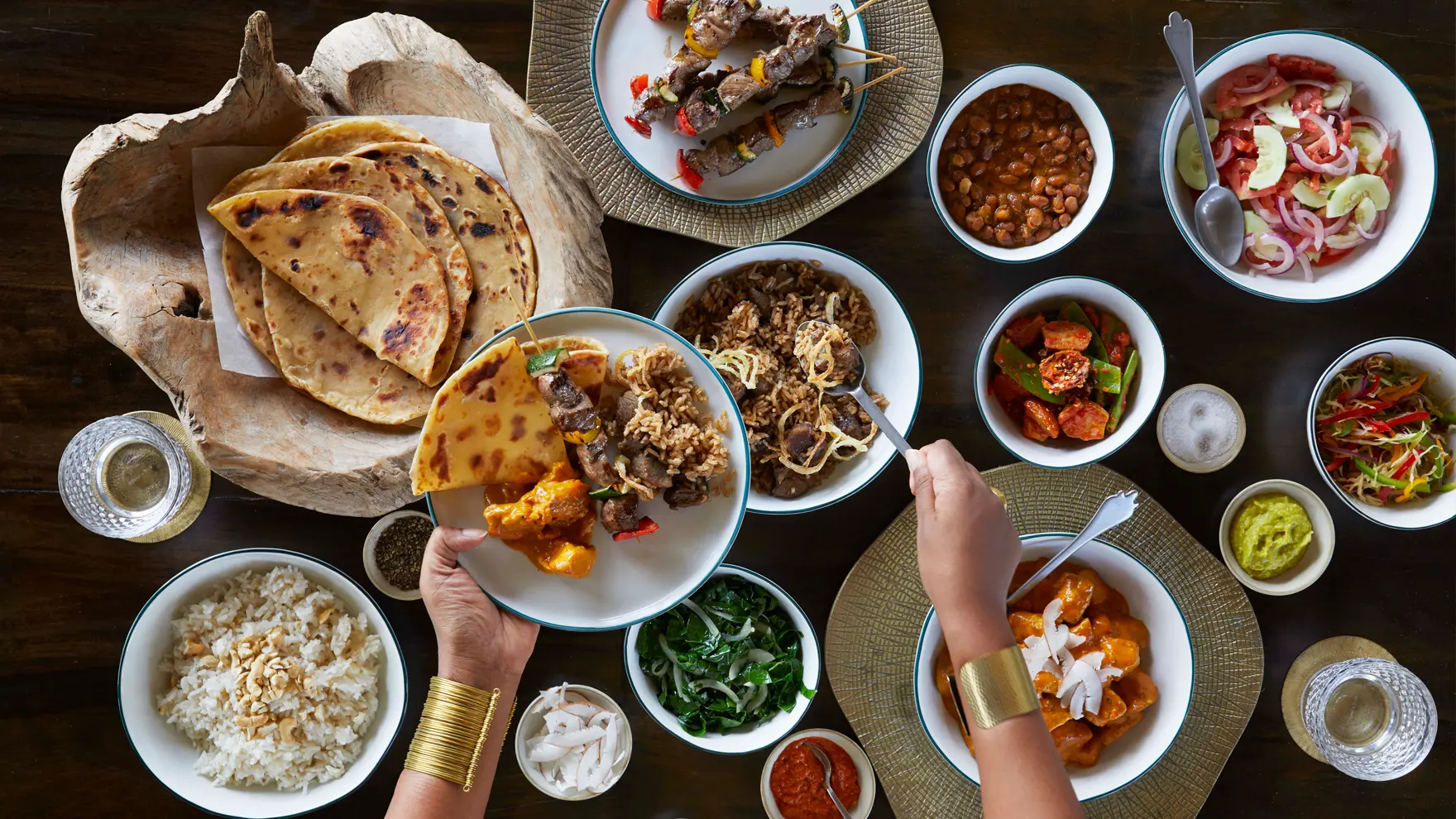 Vibrant spread of East African dishes including flatbreads, grilled skewers, rice, vegetables, and flavorful sauces on a shared dining table.