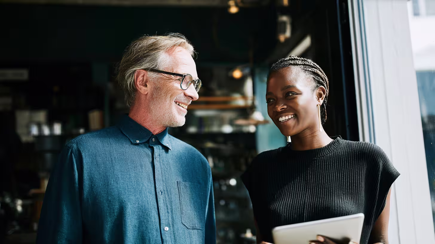 Due professionisti sorridenti discutono della loro strategia di prospezione B2B davanti a un tablet