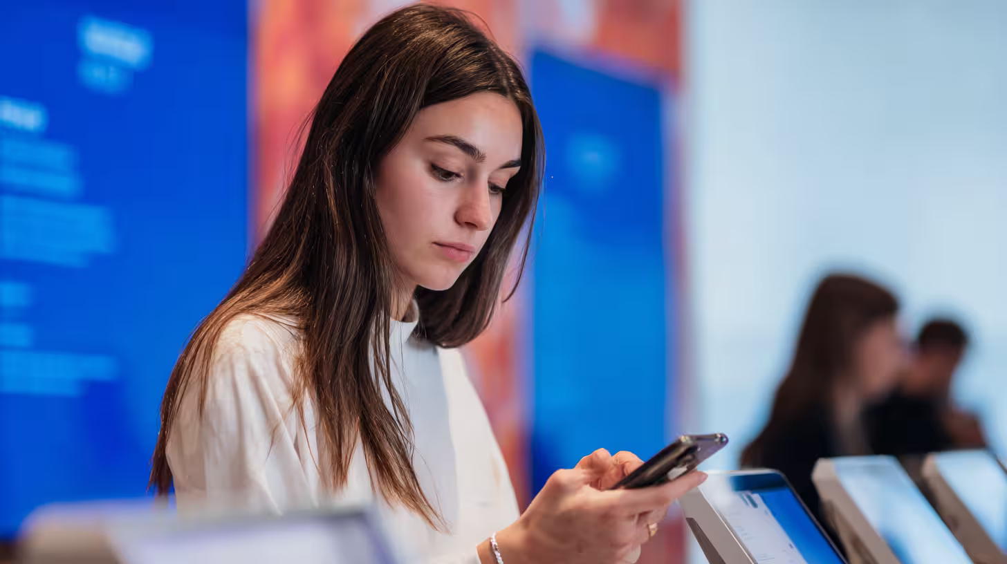Giovane donna che consulta lo smartphone tra gli schermi, illustrando la prospezione multicanale B2B