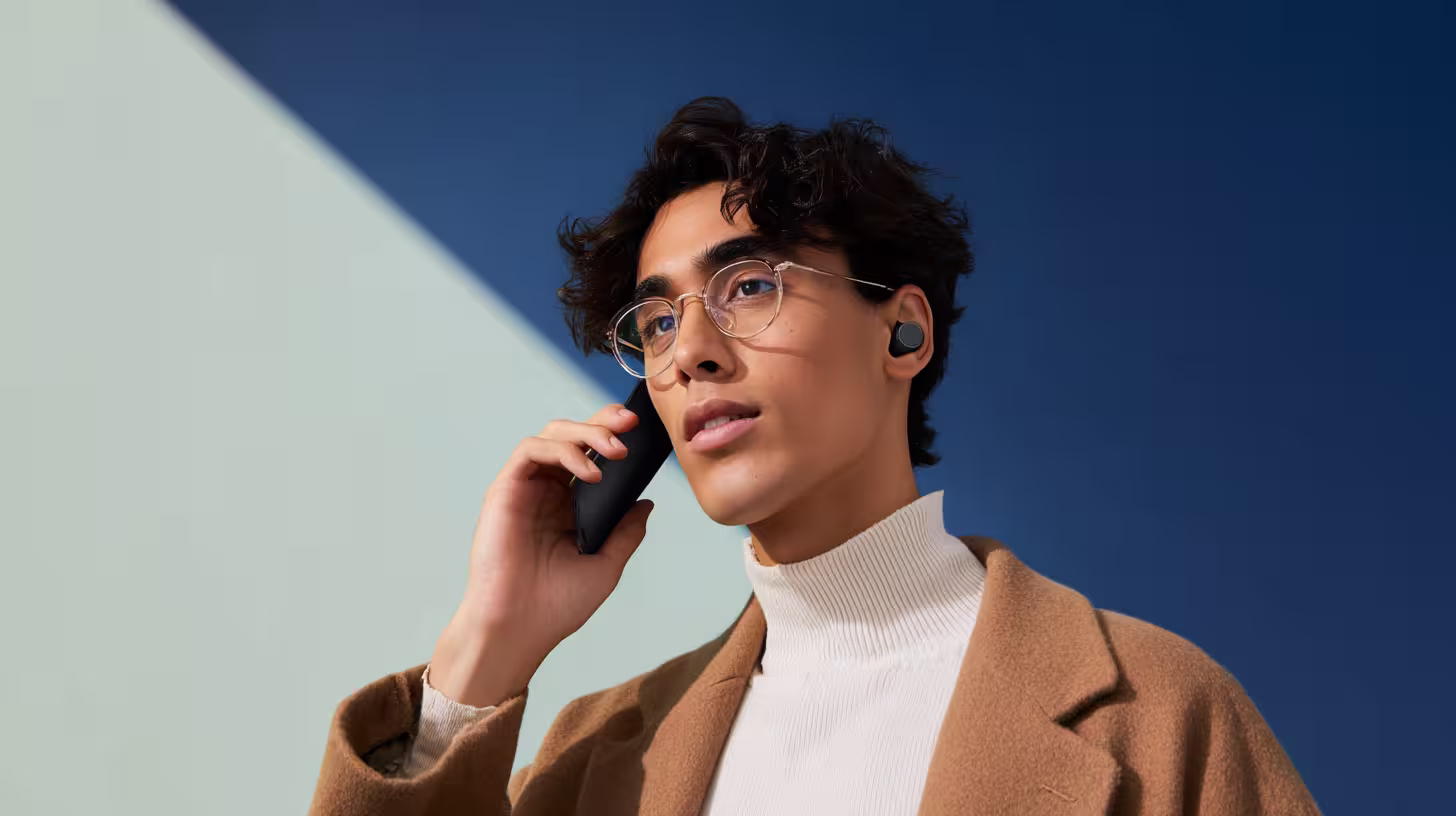 Giovane con gli occhiali che effettua una chiamata di prospezione telefonica con lo smartphone