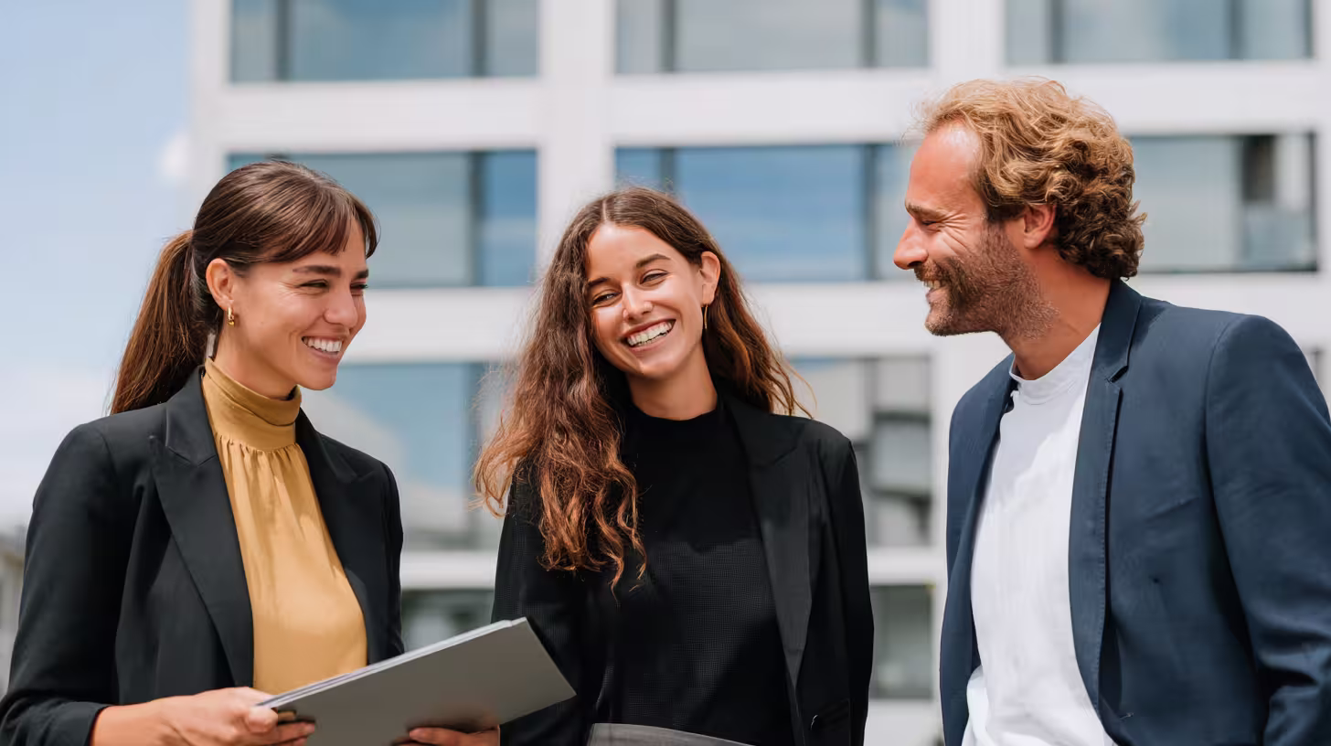 Three smiling consultants from a B2B prospecting agency standing outside an office building
