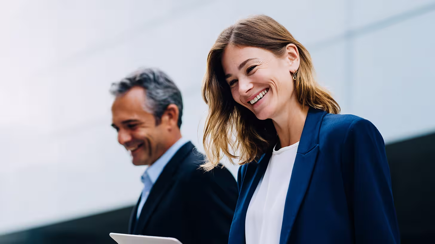 Two smiling colleagues reviewing a B2B database on a tablet