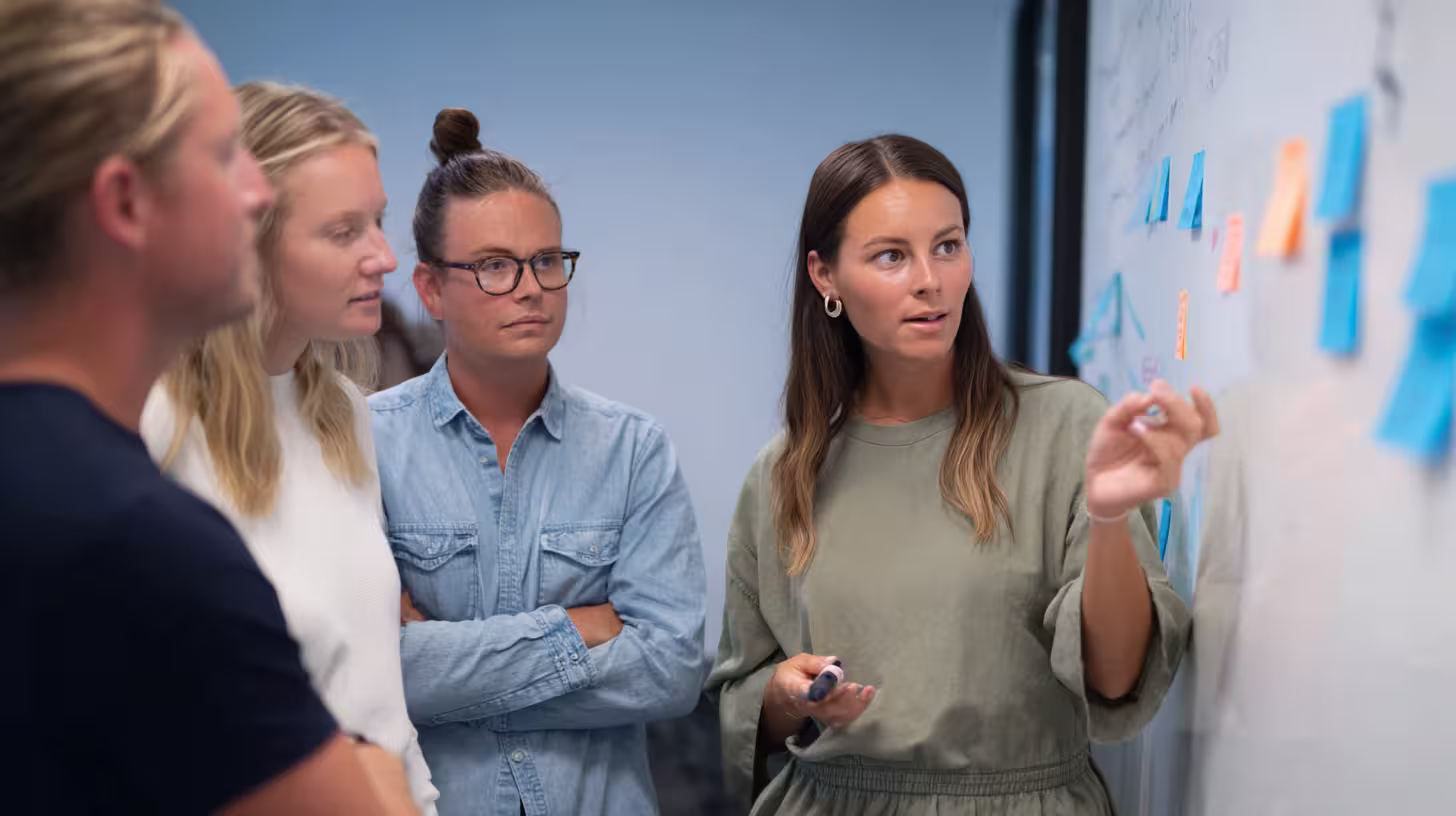 Outsourced sales team talking in front of a sticky-note board during a meeting