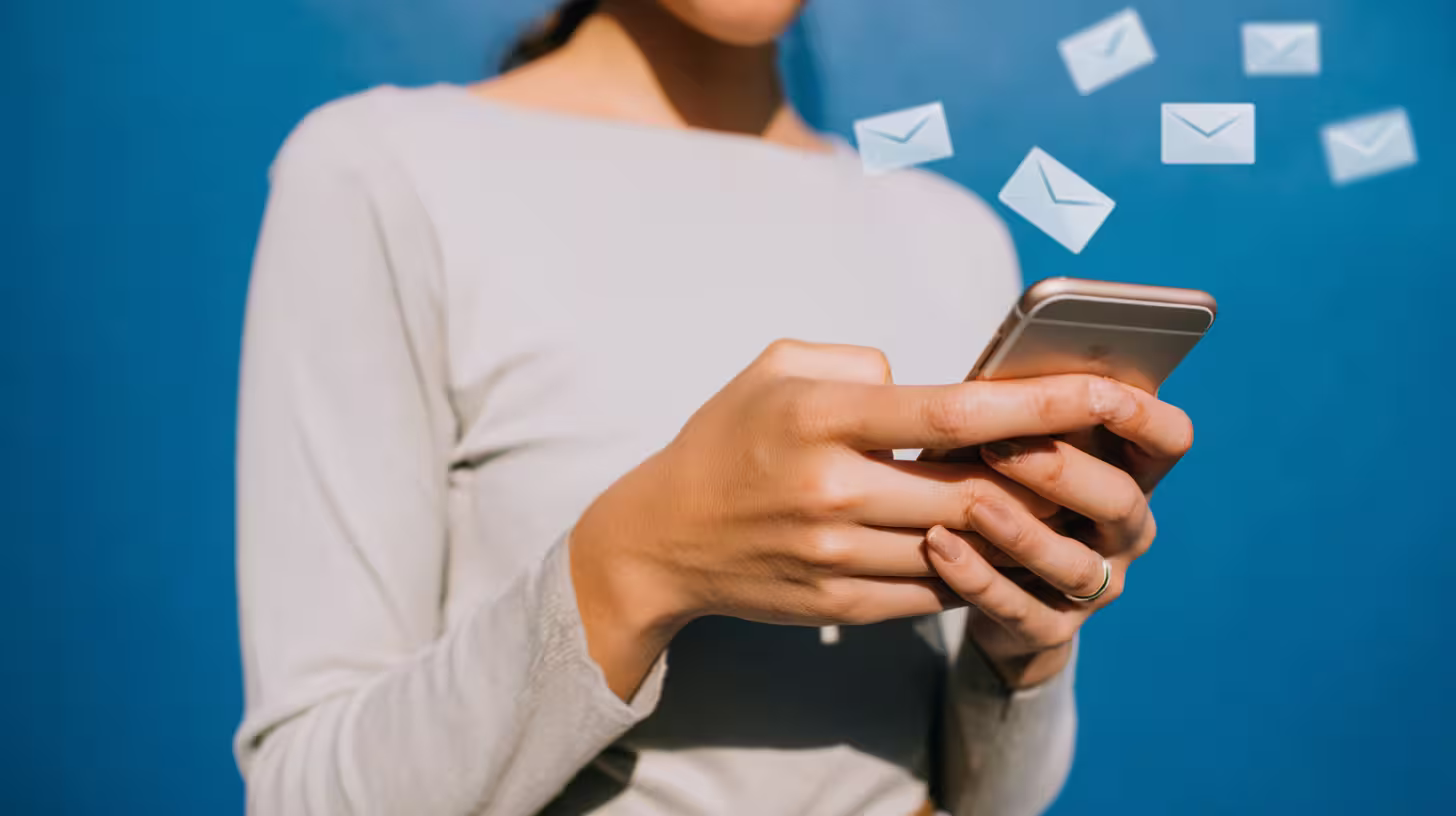 Donna che invia email dallo smartphone, a illustrare l'acquisto di un database di email