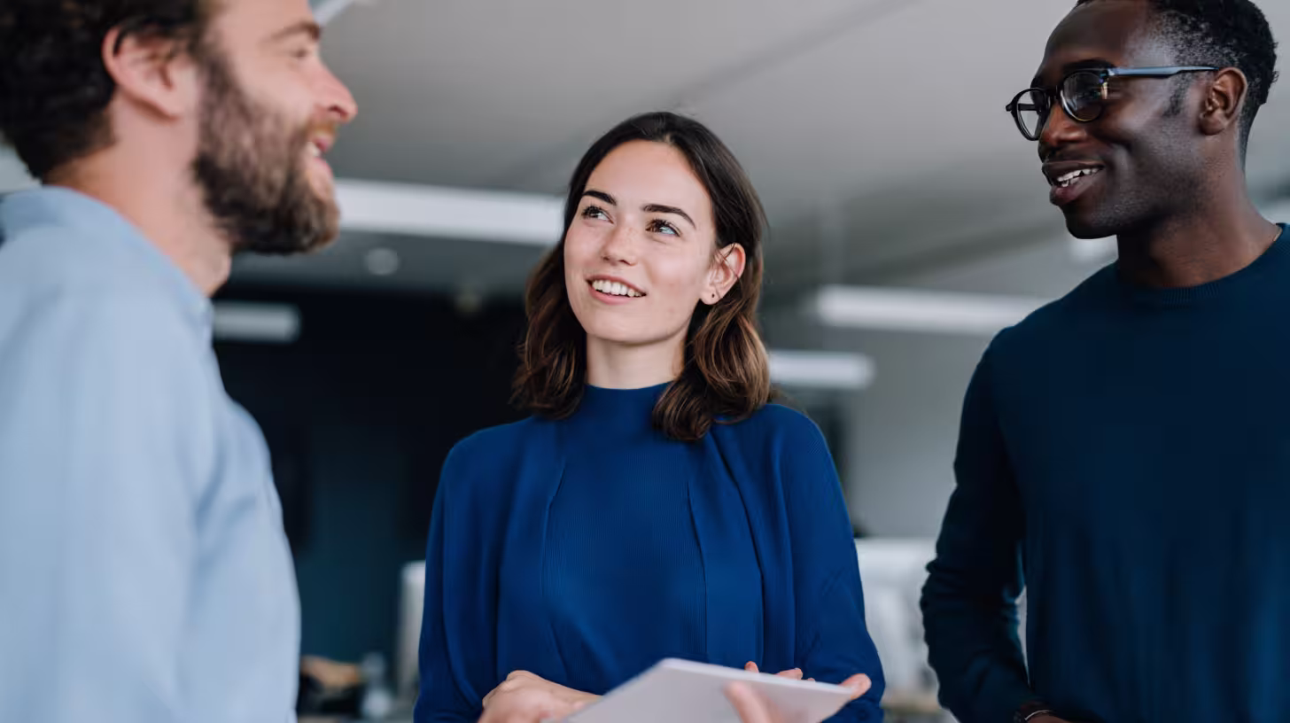 Trois commerciaux souriants préparant ensemble leurs appels de prise de rendez-vous B2B