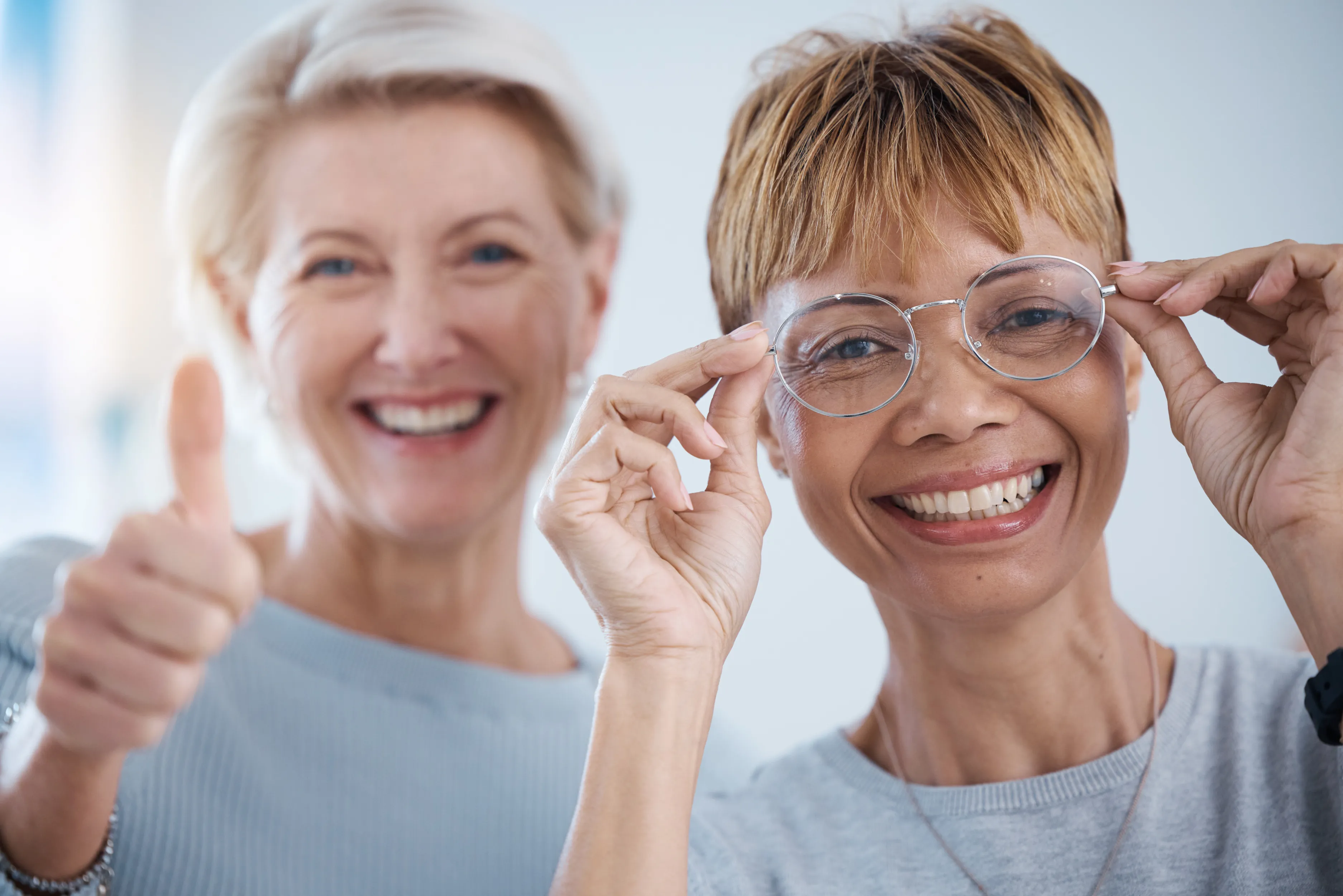 Two cheerful senior women smiling and giving thumbs up together