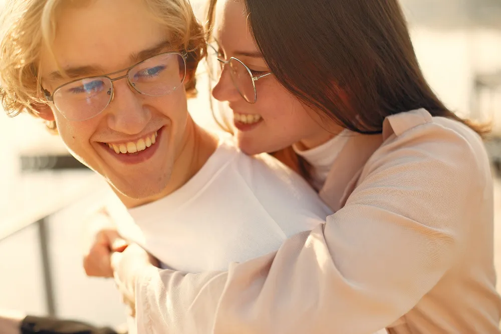Two people in white shirts smiling and embracing in warm sunlight
