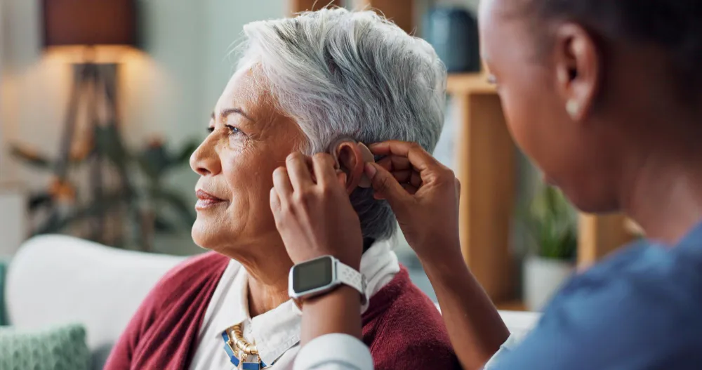 Hearing aid being adjusted for an older woman by another person