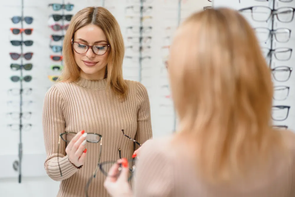 Woman trying on glasses in optical store with sunglasses display