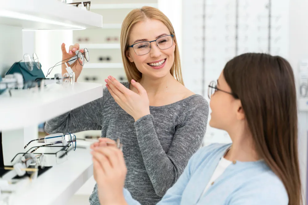 Optician helping customer choose glasses in bright, modern eyewear shop