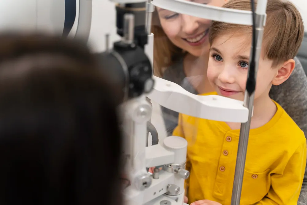Child getting eye exam with supportive adult near ophthalmology equipment