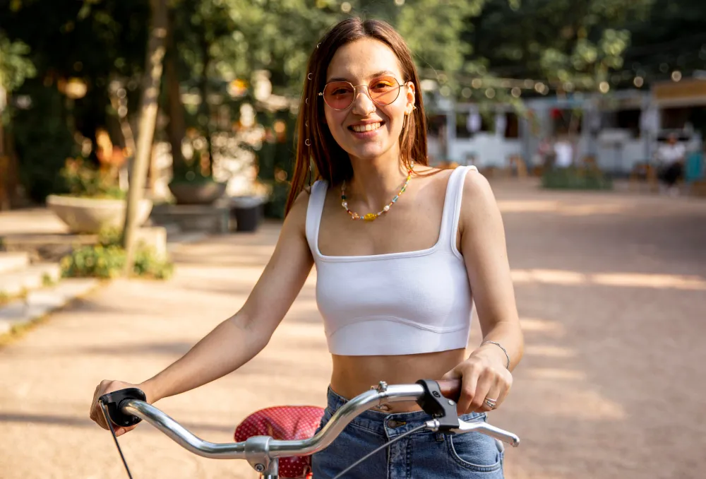 Smiling person in sunglasses with bicycle on sunny outdoor path