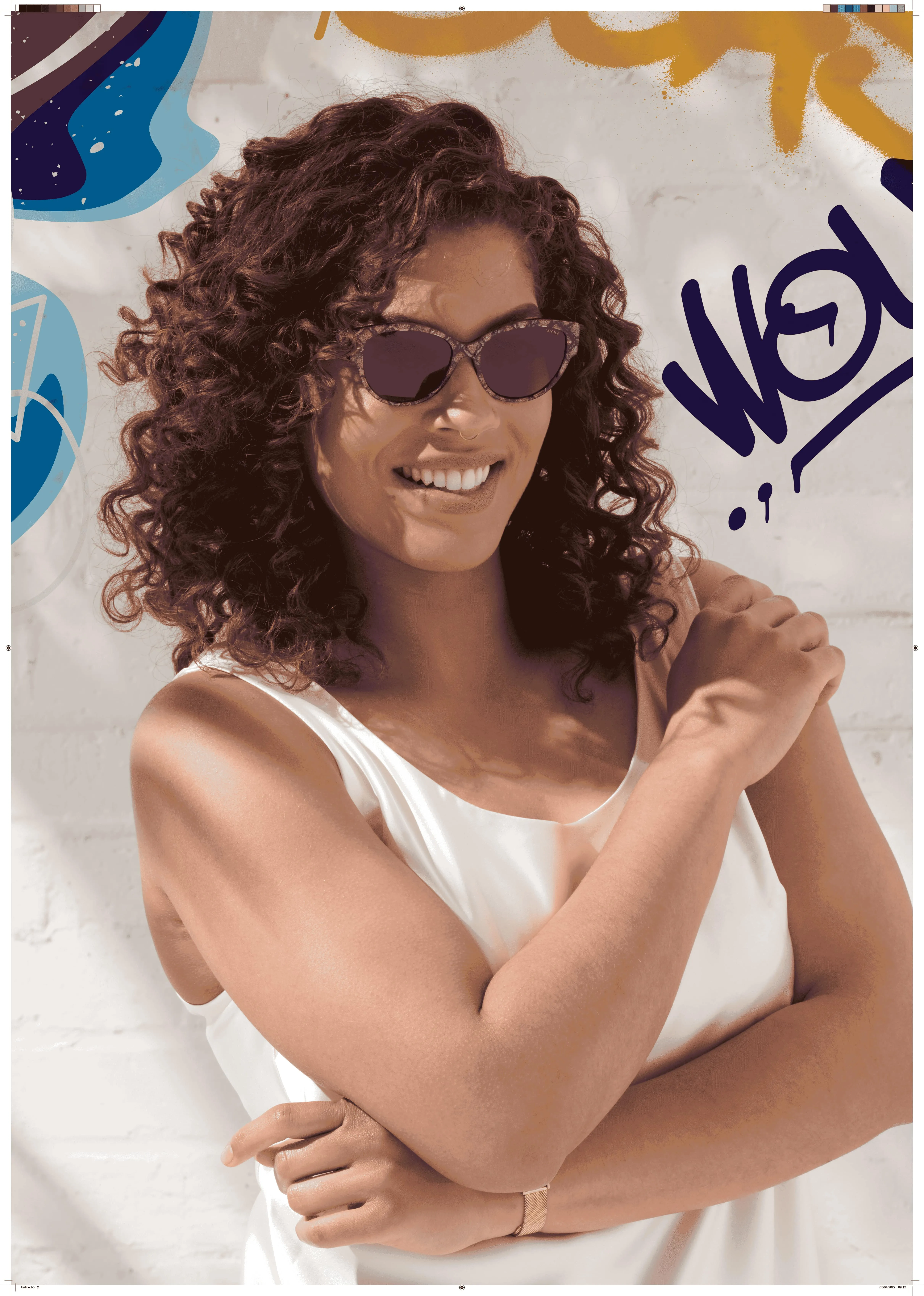 Smiling woman with curly hair and sunglasses in white top