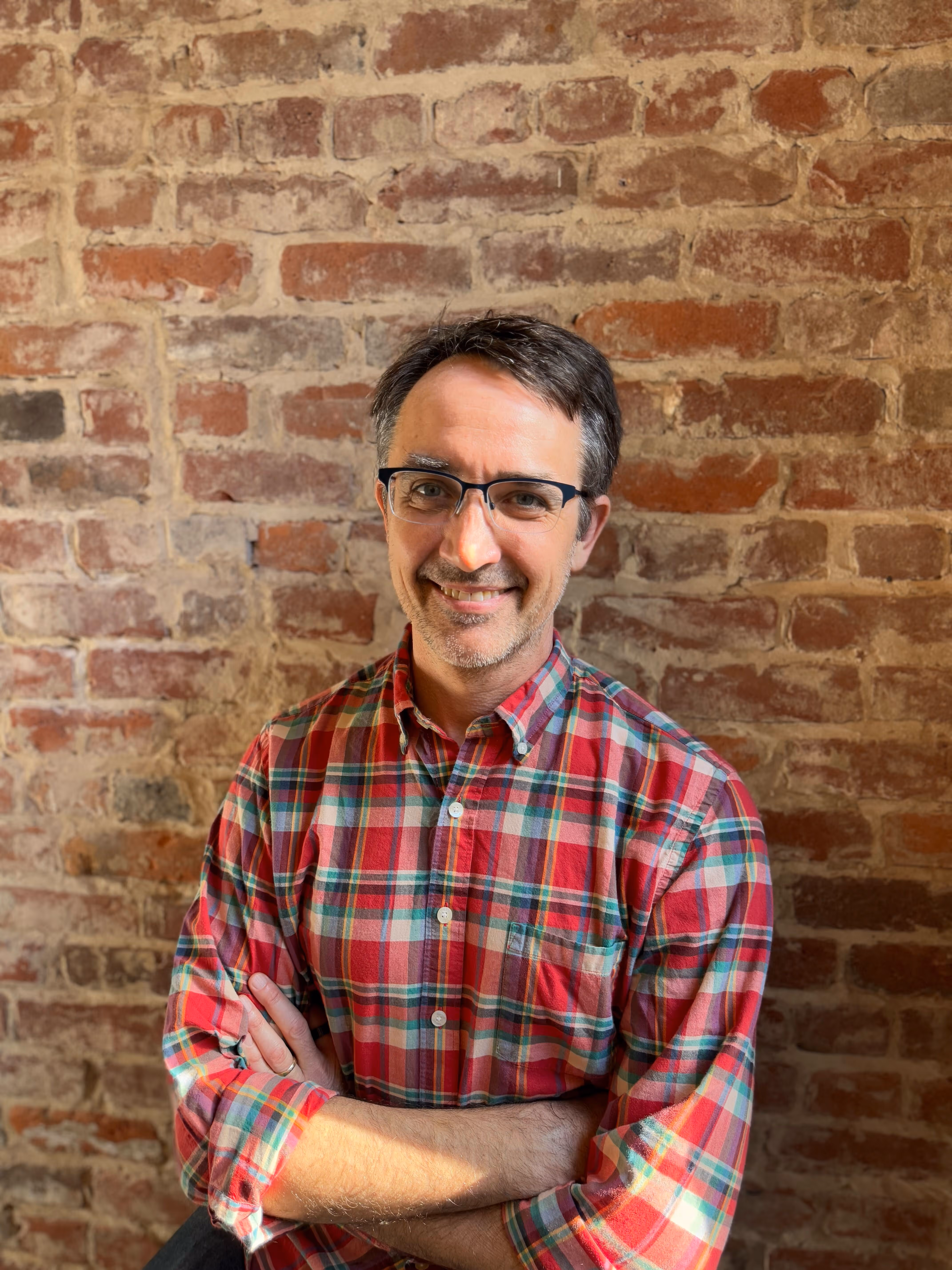headshot of smiling man in plaid shirt