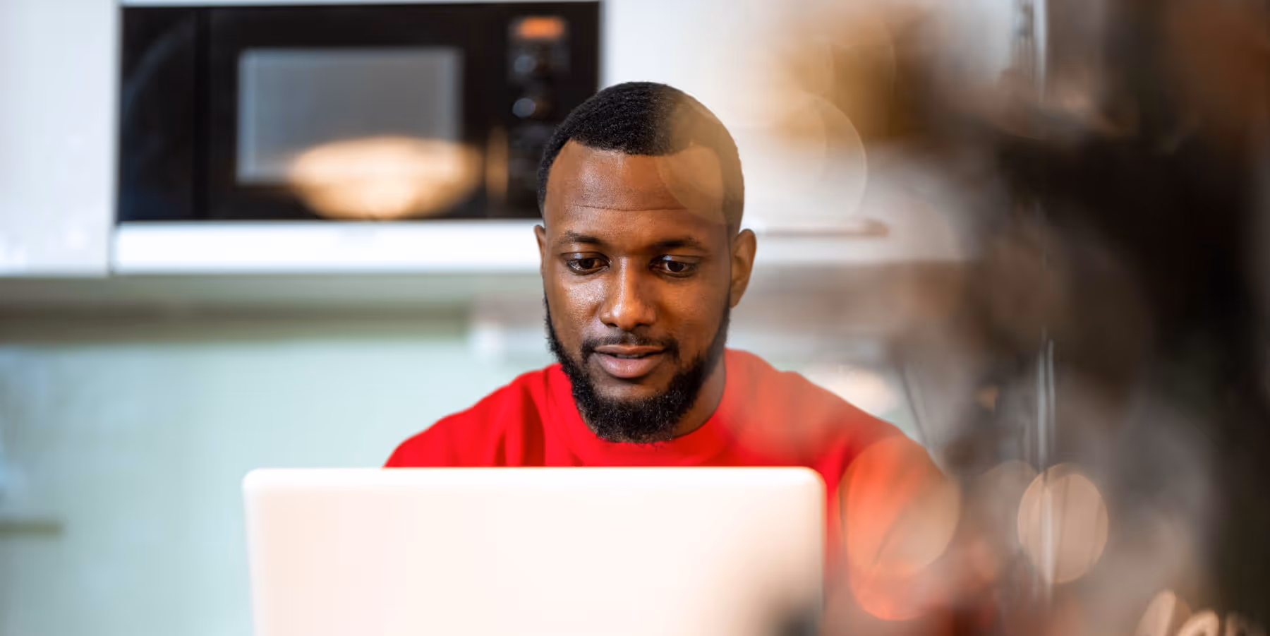 Young man with short hair and a red t shirt on a laptop