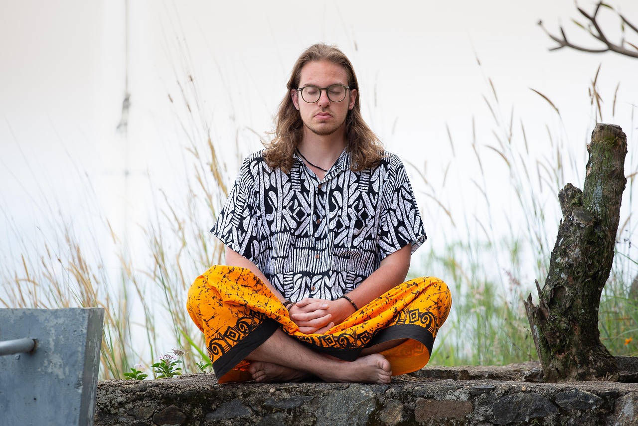A man sitting calmly outdoors with his eyes closed, breathing slowly