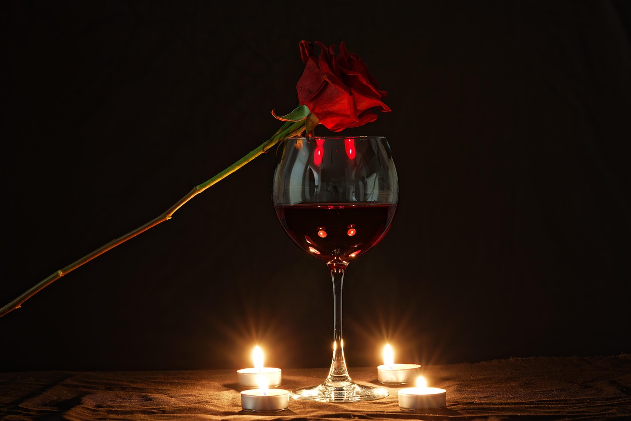 Red roses, a glass of wine and candlelight set for an anniversary celebration