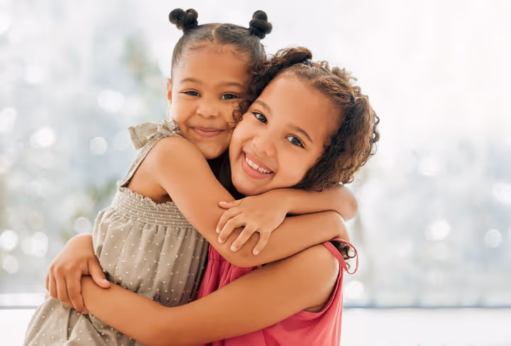 Two happy children hugging, showing the positive family support resulting from a psychoeducational evaluation.