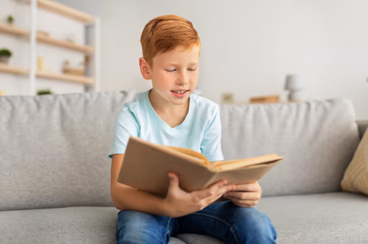 Happy boy reading a book, demonstrating engagement following educational psychologist support.