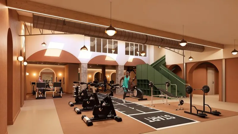 Salle de sport moderne avec équipements variés, y compris vélos d'appartement, tapis de course et poids, et une piste de course intérieure marquée 'START'.