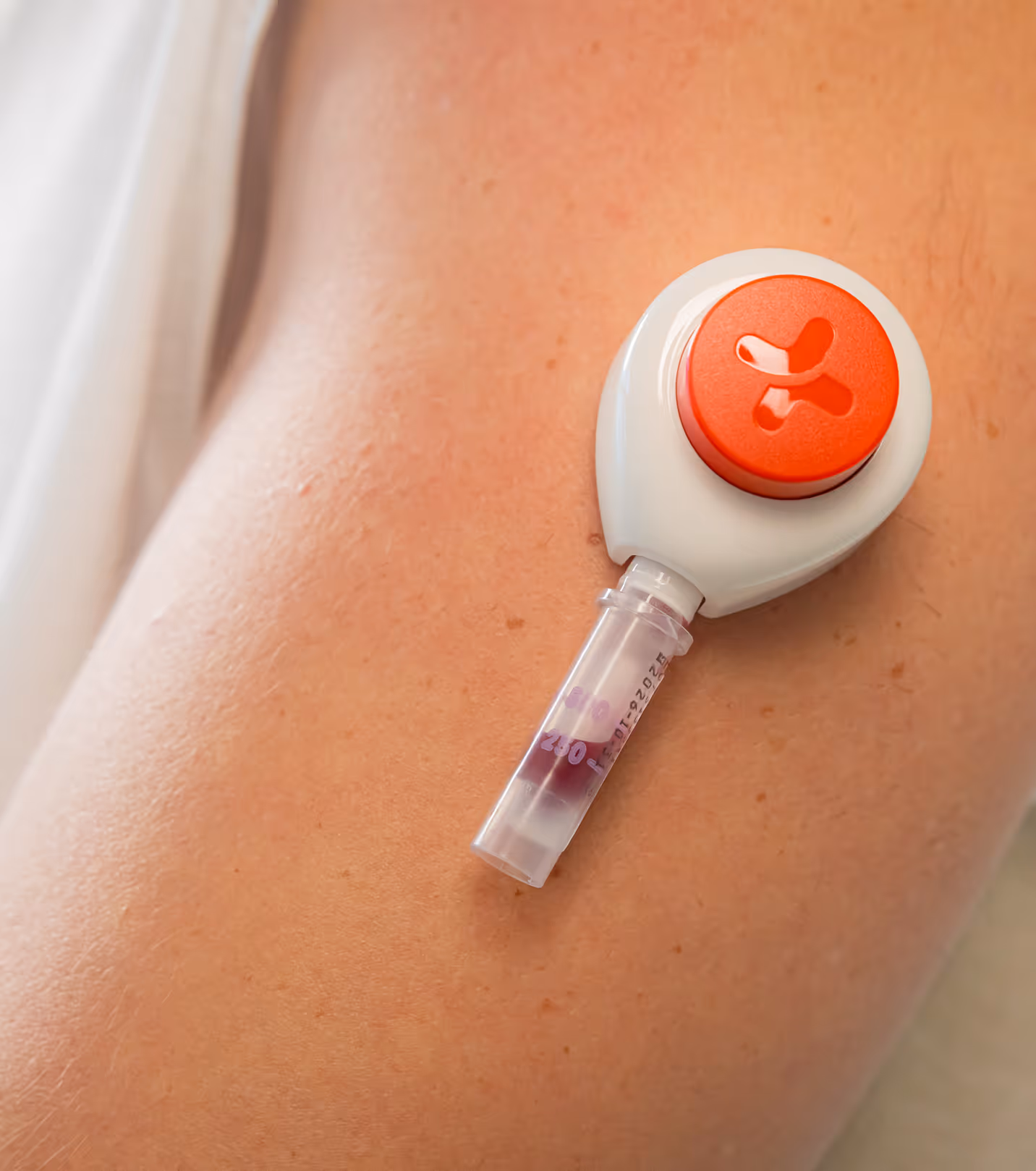 Close-up of a medical device collecting a small blood sample from a person's arm.