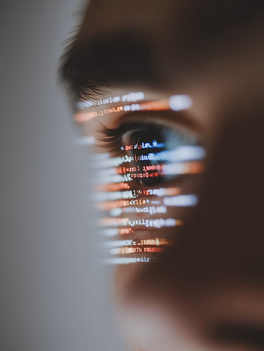 Close-up of a human eye reflecting colorful lines of computer code.