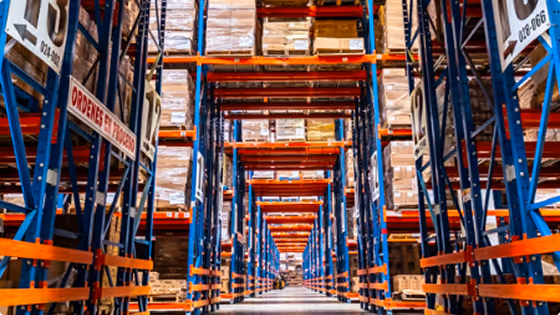 Interior of a large warehouse with tall shelves stocked with boxes and pallets.