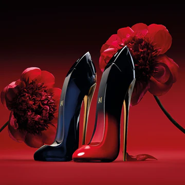 Pair of high-heeled shoes shaped like stiletto heels, one in black and the other in red, against a red background with two large red flowers.