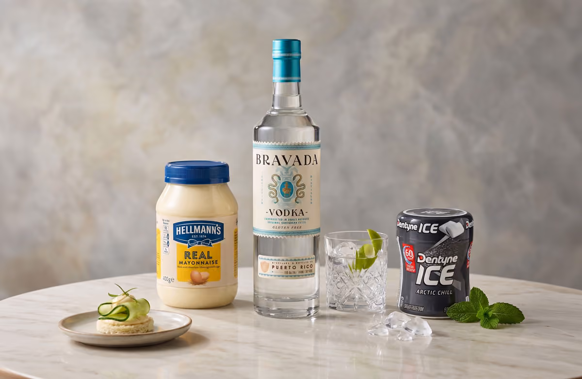 Hellmann's mayonnaise jar, Bravada vodka bottle, glass with lime and ice, Dentyne Ice gum on marble table.