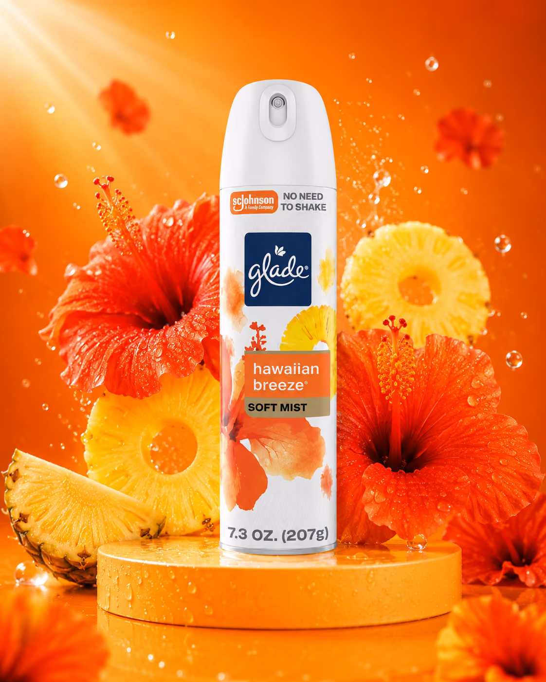 Glade Hawaiian Breeze spray can with pineapple slices and red hibiscus flowers on orange background.